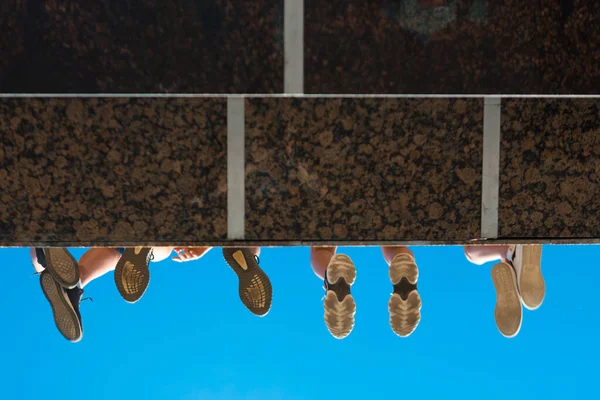 Anak laki-laki kaki di sepatu tergantung dari jembatan terhadap langit biru — Stok Foto