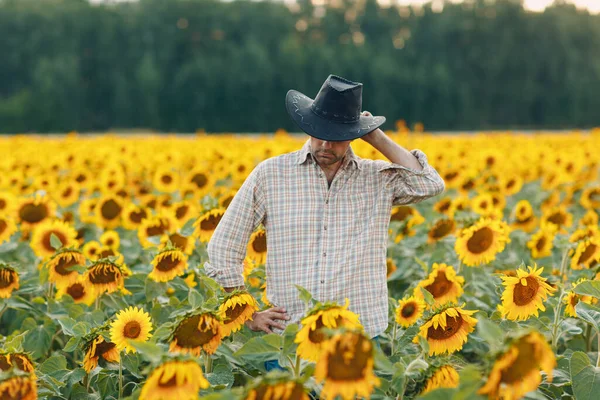 Ένας αγρότης στέκεται σε ένα χωράφι με ηλιοτρόπια. — Φωτογραφία Αρχείου