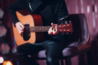 Akustik gitar çalan bir adamın elleri yakın plan.