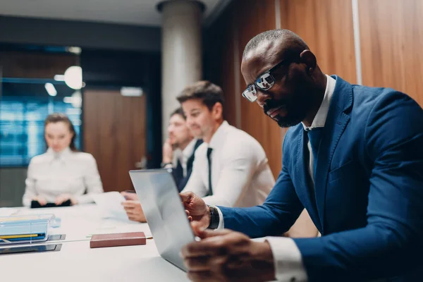 Afrikaans amerikaanse zwarte man zakenman zitten aan tafel met laptop op kantoor team mensen achtergrond. — Stockfoto