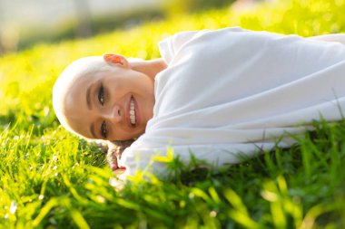 Yüzyıllık sarışın, kısa saçlı, açık havada gülümseyen genç bir kadın çimen portresinin üzerinde yatıyordu..