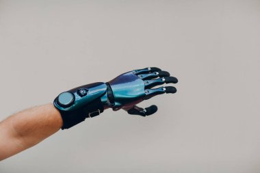 Yapay eli olan engelli bir adam elini gri arka plana yaklaştırıyor..