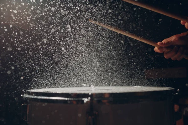 Барабанные палочки бьют ритмом по поверхности барабана брызгами воды — стоковое фото
