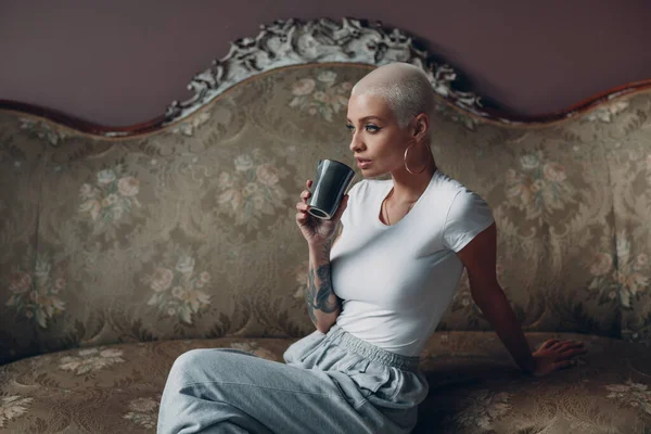 Millenial junge Frau mit kurzen blonden Haaren Porträt sitzt auf Vintage-Sofa. — Stockfoto