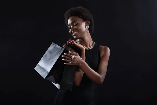 Afro-Amerikaanse vrouw heeft zwarte boodschappentassen. Verkoop en kortingen op de markt en Black Friday concept. — Stockfoto