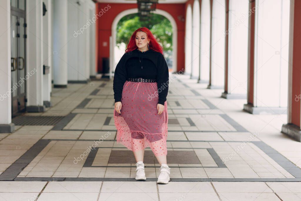 European plus size woman. Young red pink haired body positive girl