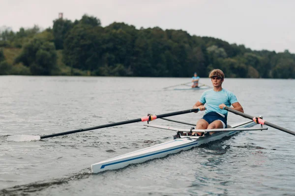 Sportsman single scull man rower rowing on boat