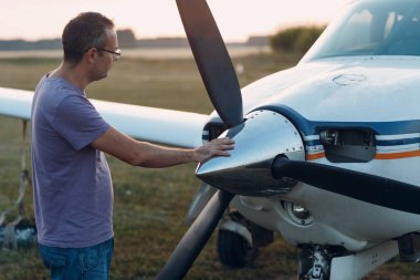 Küçük özel bir uçağın yanında duran bir pilot..
