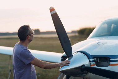 Küçük özel bir uçağın yanında duran bir pilot..