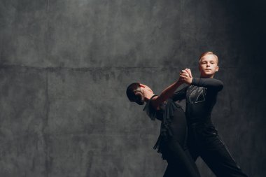 Siyah kostümlü çift Tango dansçıları balo salonunda dans ediyor.