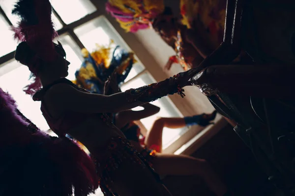Жінка в бразильському карнавальному костюмі самби з барвистим пір'ям оперення відпочиньте в старому вході з великим вікном — стокове фото