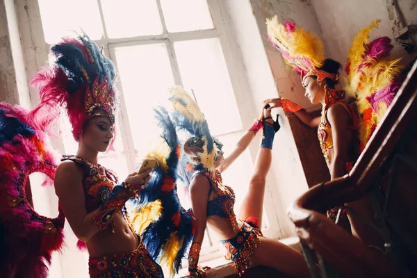 Perempuan di brazilian samba karnaval kostum dengan warna-warni bulu bulu rileks di pintu masuk tua dengan jendela besar — Stok Foto