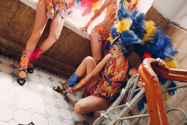 Γυναίκα στη βραζιλιάνικη στολή καρναβαλιού σάμπα με πολύχρωμα φτερά φτέρωμα χαλαρώστε στην παλιά είσοδο με μεγάλο παράθυρο — Φωτογραφία Αρχείου