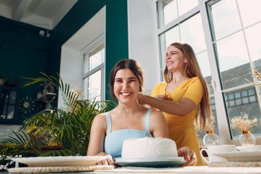 Genç kadın yüzünü kremalı pastaya daldırıyor. Mutlu yıllar..