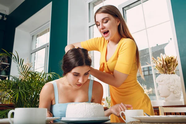 Wanita muda dips wajah dalam kue putih dengan krim. Selamat ulang tahun konsep. — Stok Foto