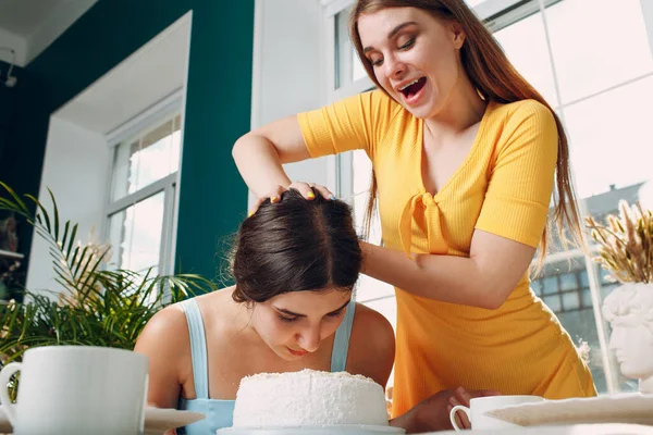 Jonge vrouw dompelt gezicht in witte taart met room. Gelukkige verjaardag concept. — Stockfoto