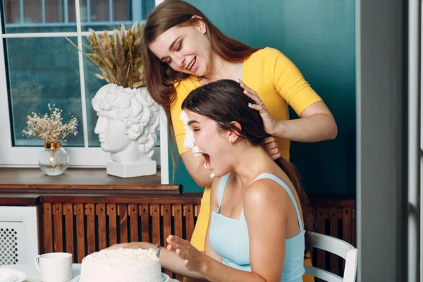 Junge Frau taucht Gesicht in weißen Kuchen mit Sahne. Happy Birthday Konzept. — Stockfoto