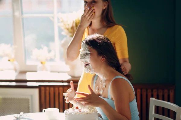 젊은 여자는 얼굴을 크림 으로 화이트 케이크 에 찍는다. 생일 축하 해. — 스톡 사진