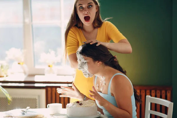 Mujer joven sumerge la cara en pastel blanco con crema. Feliz cumpleaños concepto. — Foto de Stock