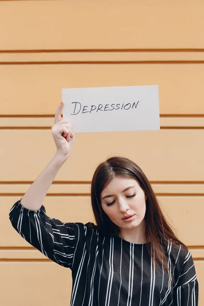 Frau hält weißes Blatt Papier mit der Aufschrift Depression in der Hand gelben Hintergrund. — Stockfoto