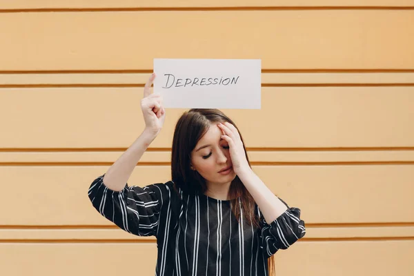 Frau hält weißes Blatt Papier mit der Aufschrift Depression in der Hand gelben Hintergrund. — Stockfoto