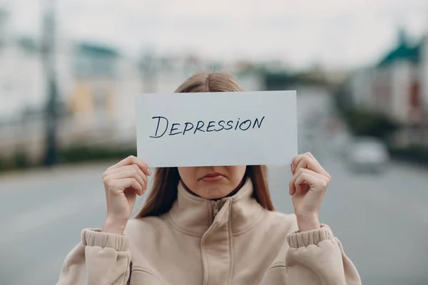 Droevige vrouw met wit vel papier gelabeld woord depressie in de hand. — Stockfoto