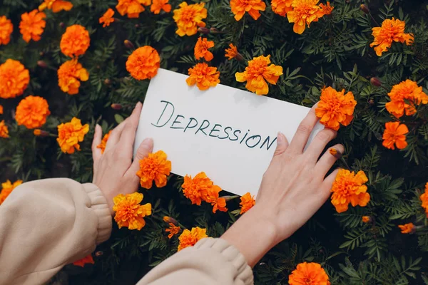 Mulher segura na mão folha branca de papel com a palavra Depressão no fundo da flor — Fotografia de Stock