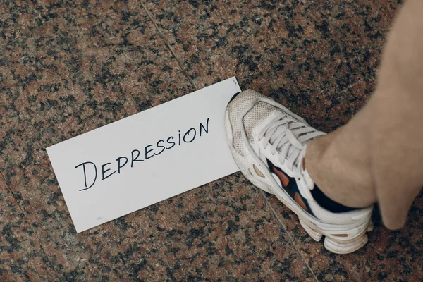Wanita menginjak selembar kertas putih dengan kata Depresi dan kaki di atasnya — Stok Foto