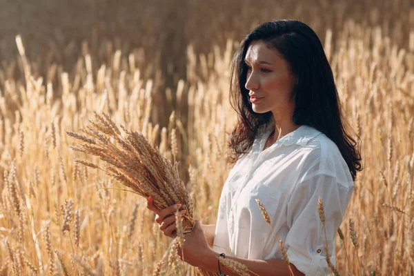 Giovane donna bordo illuminato ritratto tenendo covone di spighe di grano in campo agricolo — Foto Stock