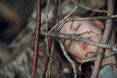 Parkta, kuru ağaç dallarının altında güzel bir genç kadın.