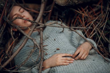 Parkta, kuru ağaç dallarının altında güzel bir genç kadın.