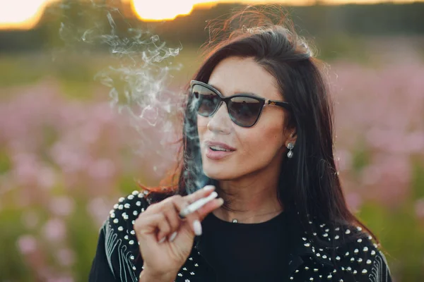 Mujer joven fumando en el floreciente campo de flores de Sally. Flores y mujer lila. —  Fotos de Stock