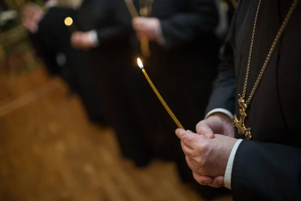 Ortodoxo sacerdote cristiano rezando en la iglesia con vela encendida en las manos. —  Fotos de Stock