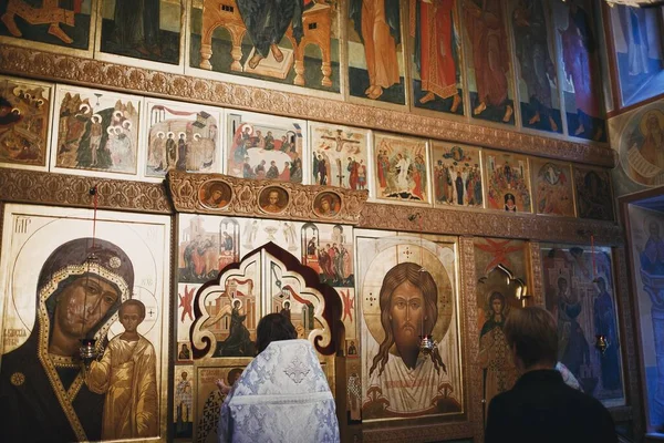 Sacerdote cristão ortodoxo e paroquiano orando em ícones na igreja. — Fotografia de Stock