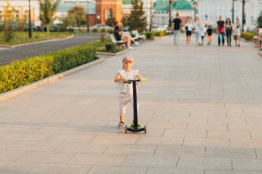Küçük kız şehir caddesinde scooter kullanıyor..