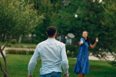 Genç bir çift parkta badminton oynuyor.