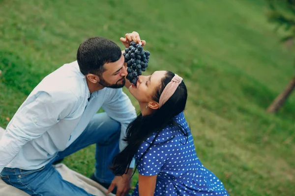 Jeune femme adulte et homme couple pique-nique avec du raisin au pré d'herbe verte dans le parc — Photo