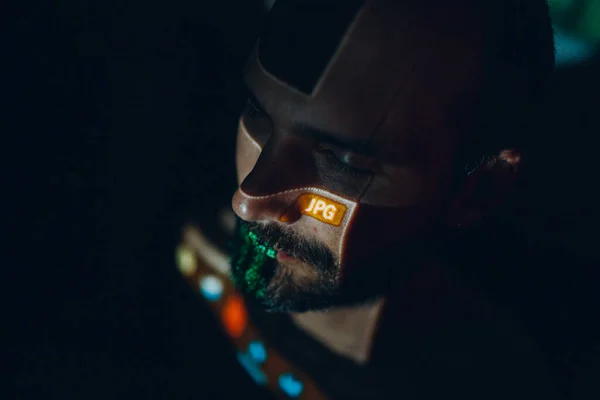 Joven hombre cyberpunk con letras en la cara en la oscuridad. — Foto de Stock