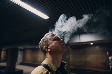 Kafkasyalı bir gencin portresi. Karanlıkta açık renkli e-sigara içiyor.