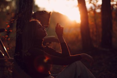 Günbatımında sonbahar parkında bisiklet süren mutlu, aktif genç bir kadın.