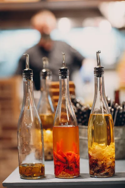 Aceite de oliva en botella con ajo, pimiento rojo y romero sobre mesa en pizzería — Foto de Stock