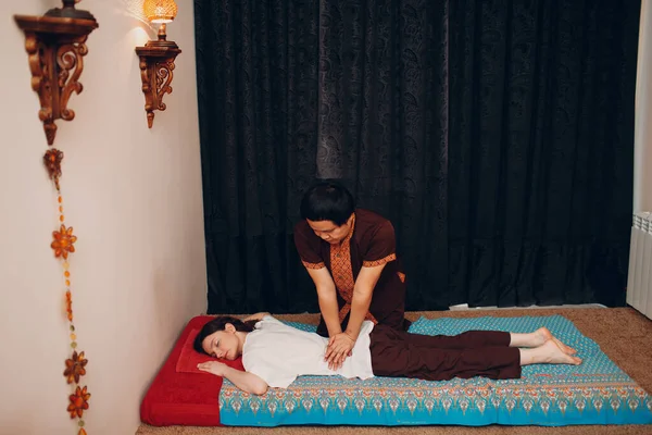 Thai man making classical thai massage procedure to young woman at beauty spa — Stock Photo, Image