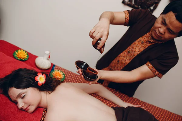 Thai man making classical thai massage procedure to young woman at beauty spa — Stock Photo, Image