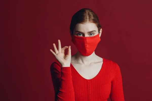 身穿防护医疗面罩、在红色背景下被隔离的年轻女性的工作室肖像。瑜珈、沉着、禅定和冥想- -一个covid-19 pandemia概念 — 图库照片
