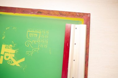 Giyim fabrikasında seri ipek ekran baskı işlemi. Çerçeve, cam sileceği ve plastisol rengi