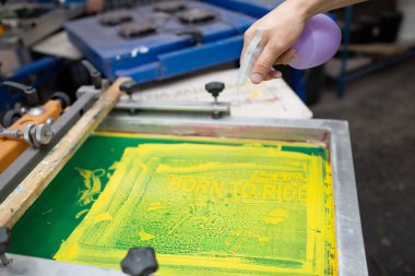 Giyim fabrikasında seri ipek ekran baskı işlemi. Temizleme Çerçevesi, cam sileceği ve plastisol rengi