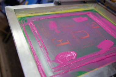 Giyim fabrikasında seri ipek ekran baskı işlemi. Çerçeve, cam sileceği ve plastisol rengi