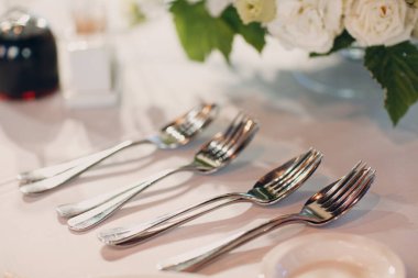 Restoranda beyaz masa örtüleri ve çiçek dekoru olan yuvarlak masalar.