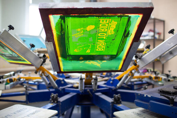 Сериграфический процесс шелкографии на швейной фабрике. Каркас, скребок и пластизол цвета красок