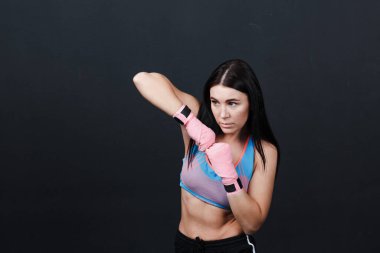 Sporcu Muay Taylandlı kadın boksör eğitim stüdyosunda siyah arka planda poz veriyor..